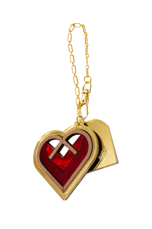 Red and gold bag charm with a heart-shaped charm and gold chain on a white background. Laser cut charm made from acrylic, plywood and walnut wood