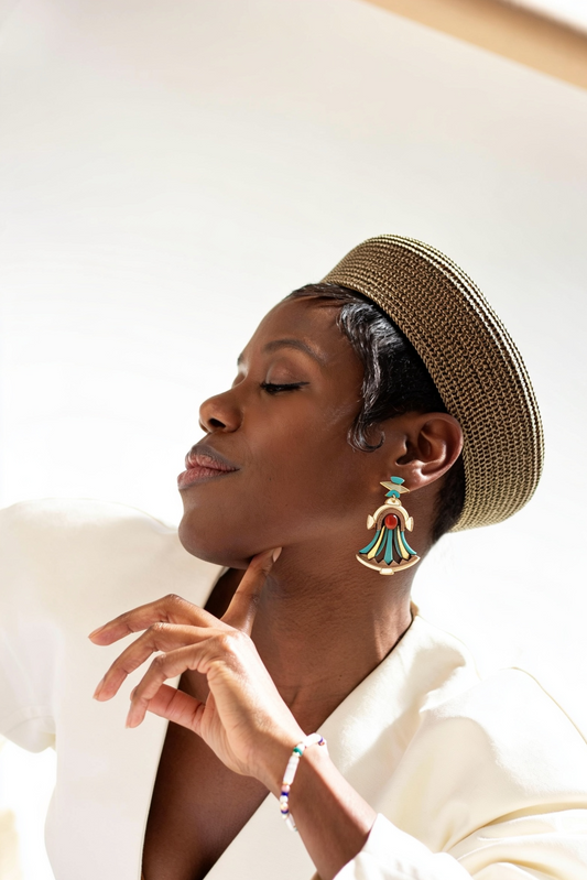Woman wearing cleopatra earrings, made from walnut, carnelian cabochon and acrylic with a straw hat and white outfit with a blurred background