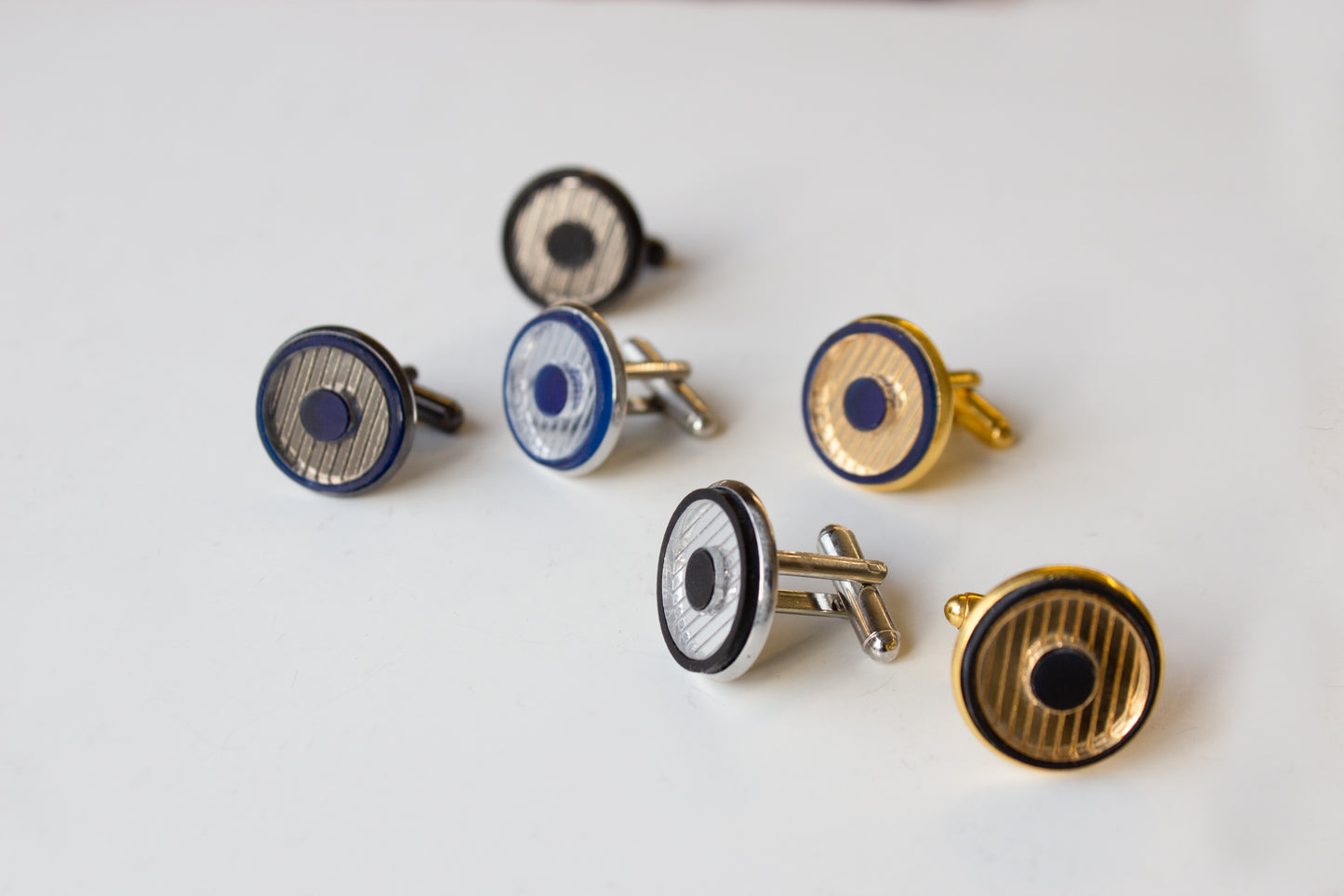 Set of cufflinks with blue, gold, and silver designs on a white background