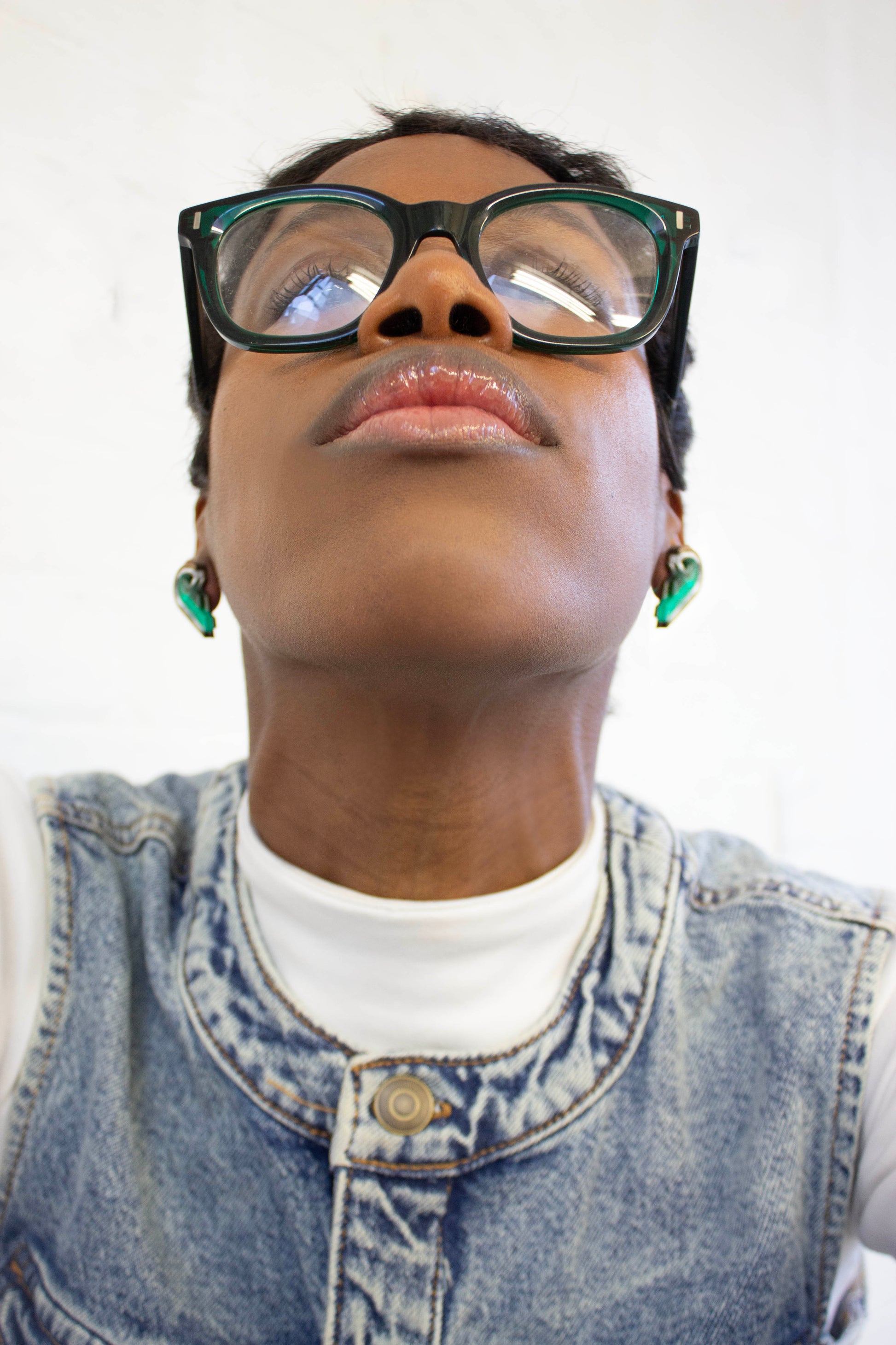 Person wearing green acrylic earrings resembling to halves of a heart shape