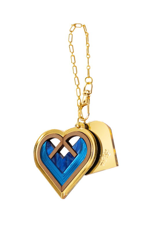 Gold heart-shaped bag charm with blue interior on a white background. Laser cut bag charm made from acrylic, walnut wood and plywood