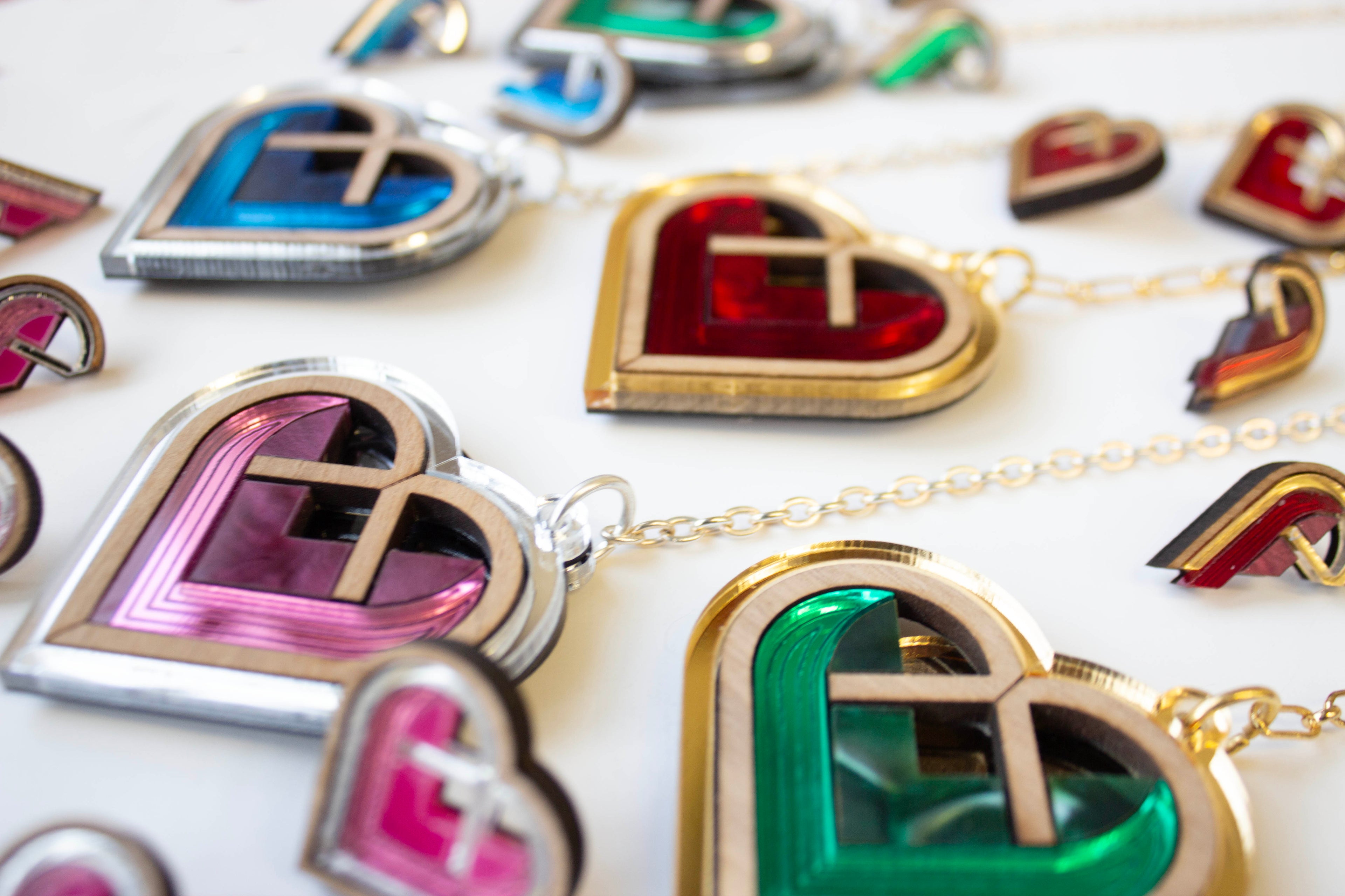 Colorful heart-shaped acrylic bag charms and studs on a white background