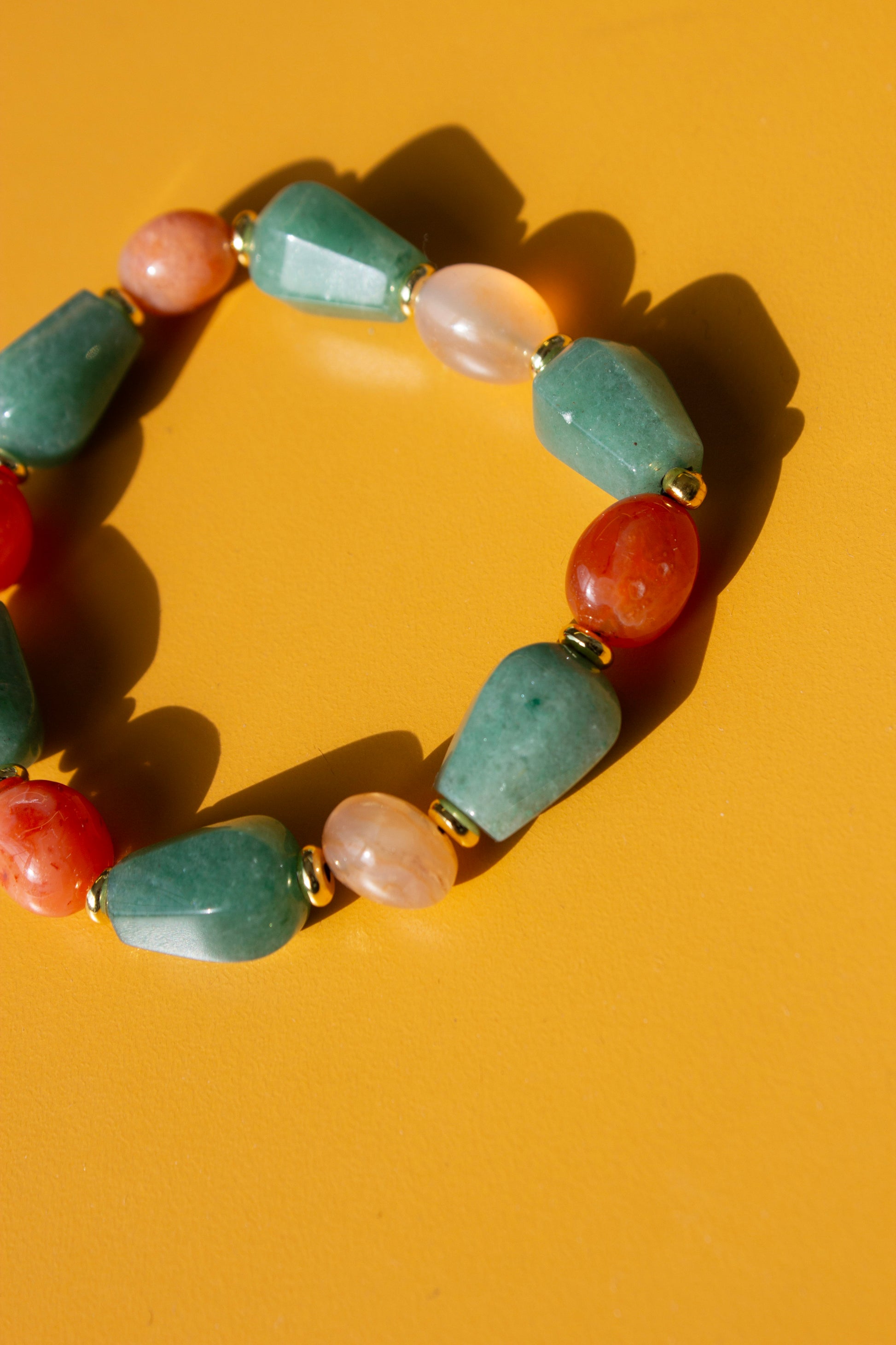 Bracelet with multicolored aventurine and carnelian beads on a yellow background