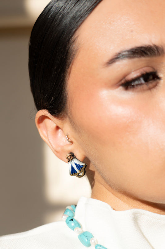 Close-up of a person wearing a blue and white lotus earring with a blurred background