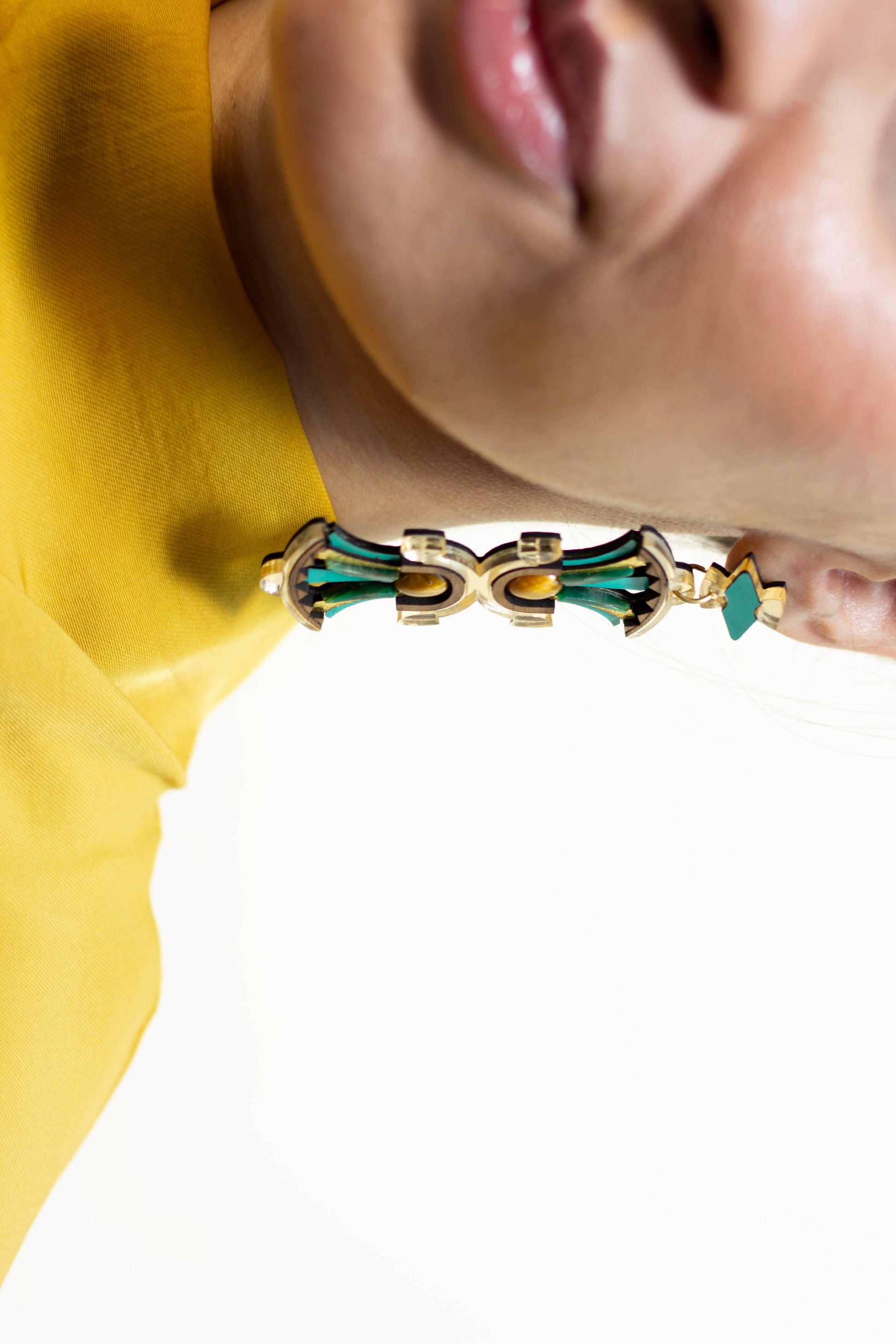 Close-up of a person wearing a gold and turquoise earring with a blurred background