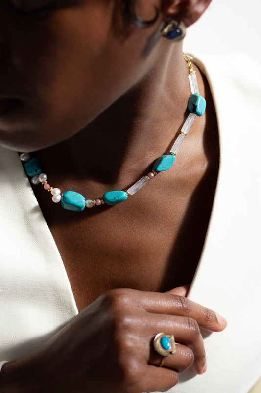 Necklace with turquoise beads and a ring on a person's hand