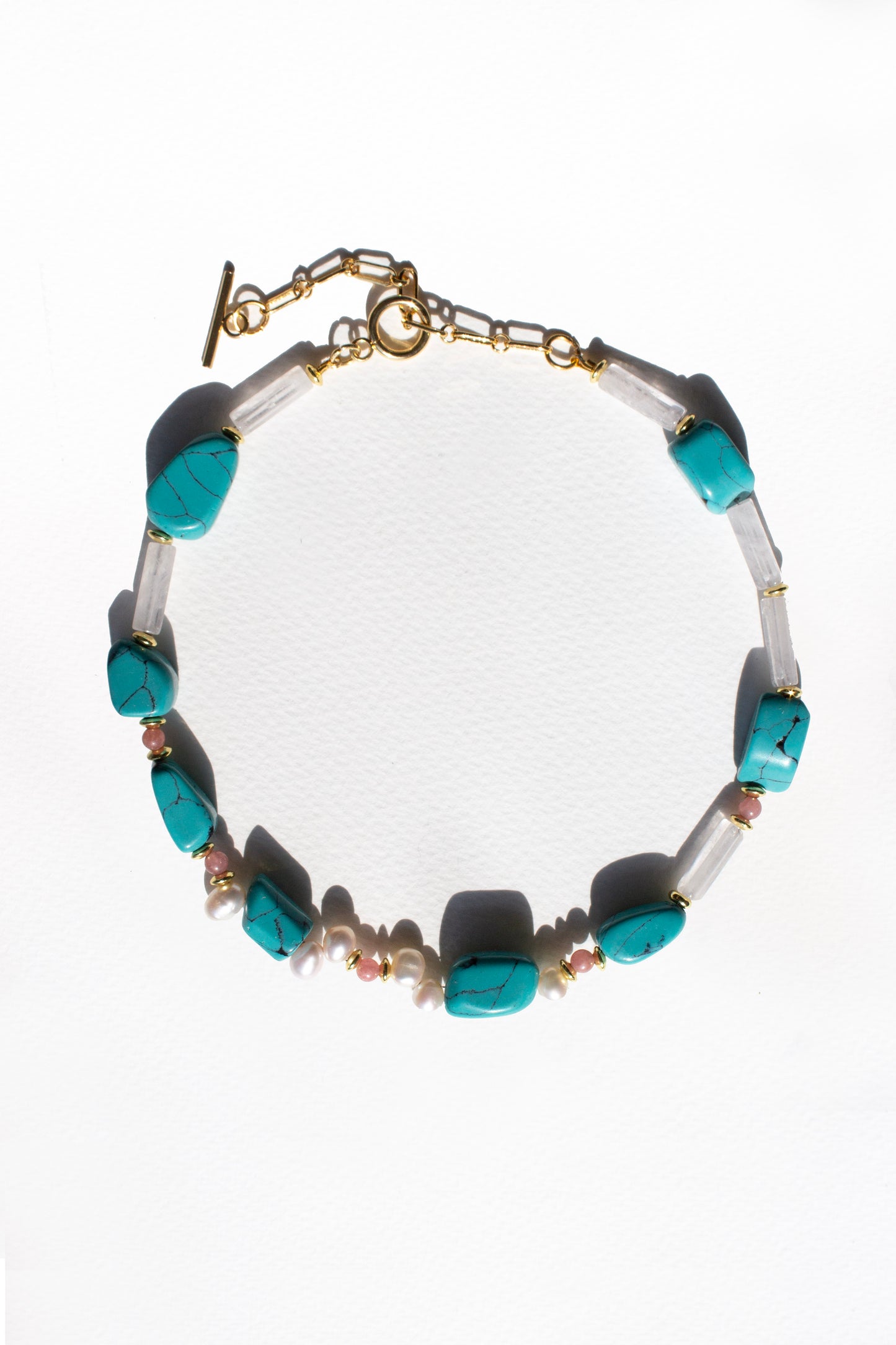 Necklace with turquoise, rose quartz and pearl beads on a white background