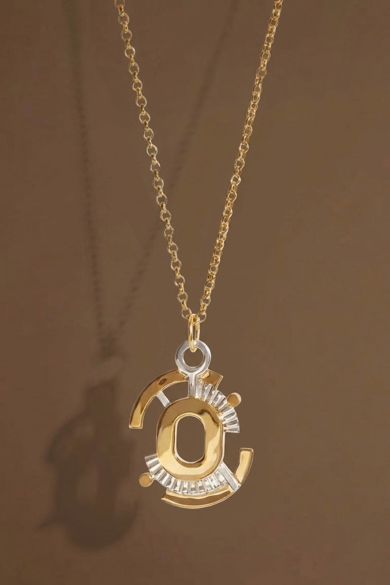 Gold Gaia necklace pendant on a brown background