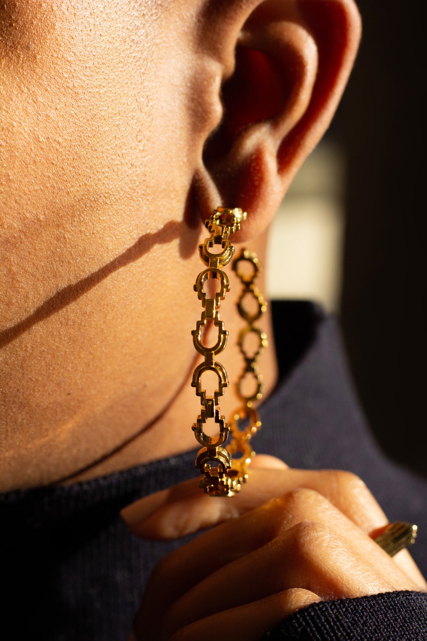 Close up of large gold Mayan hoops worn on model